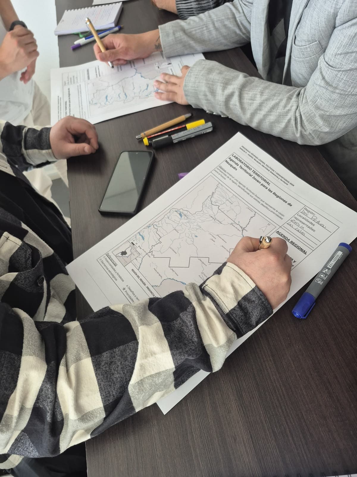 Jóvenes presentando ideas y proyectos comunitarios alrededor de una mesa de trabajo